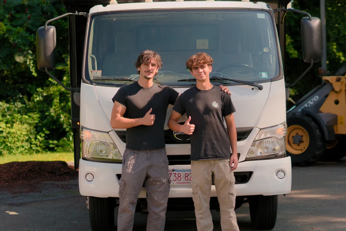 Henrique and Filipe, the brothers who own The Junk Heroes, giving a thumbs up in front of their junk removal truck in Salem, MA